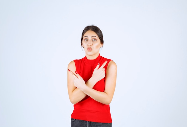 Ragazza in camicia rossa che punta su entrambi i lati.