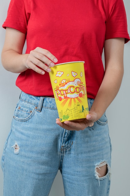 Ragazza in camicia rossa che tiene una scatola di popcorn