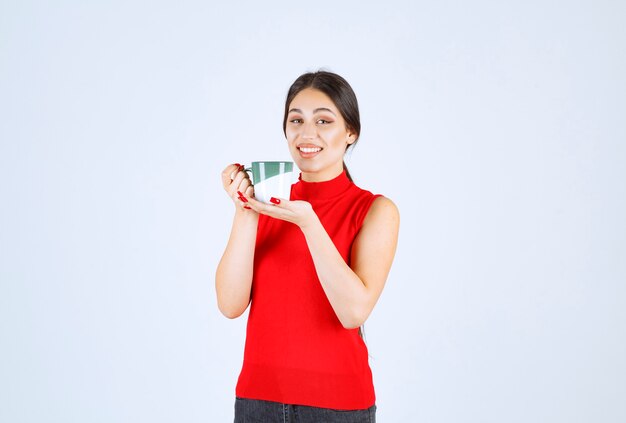 Ragazza in camicia rossa che tiene una tazza da caffè.