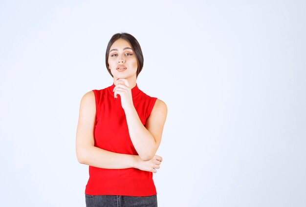 Ragazza in camicia rossa pensando e analizzando.