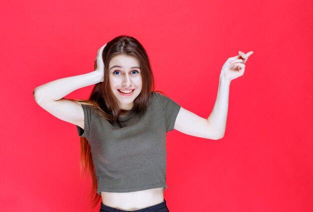 Ragazza in camicia verde che punta a qualcosa a est.