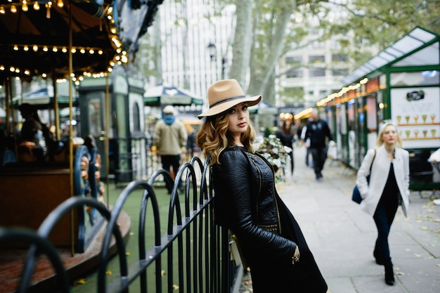 Ragazza in cappello beige si appoggia alla recinzione in acciaio sulla strada