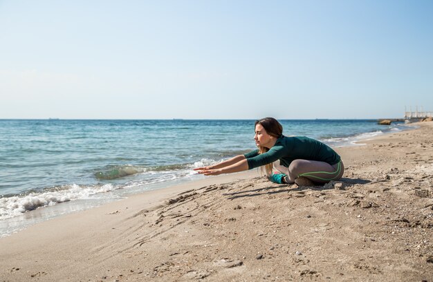 Ragazza in fitness abbigliamento sportivo in riva al mare ascoltando musica, motivazione sportiva, sport, fitness