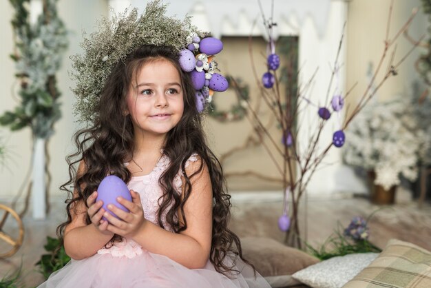 Ragazza in ghirlanda di fiori con uovo di Pasqua