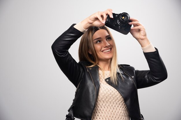 Ragazza in giacca di pelle che controlla la sua cronologia fotografica sulla fotocamera.