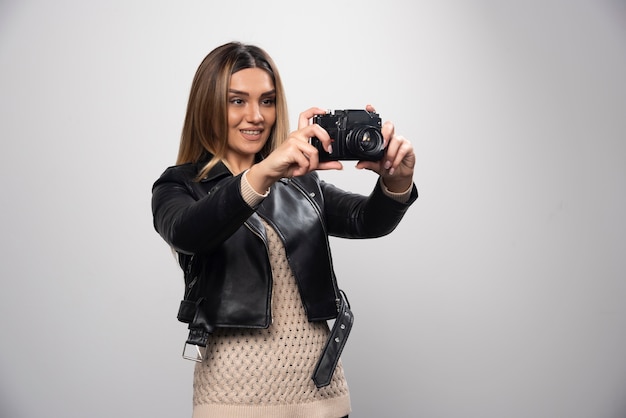 Ragazza in giacca di pelle che controlla la sua cronologia fotografica sulla fotocamera