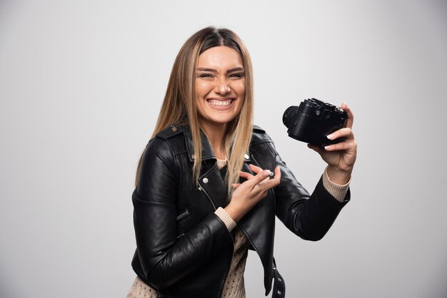 Ragazza in giacca di pelle che controlla la sua cronologia fotografica sulla fotocamera