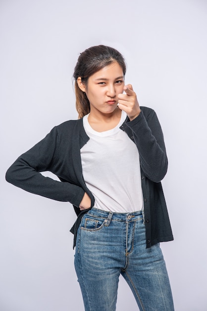 Ragazza in jeans elasticizzati bianchi e un cartello fatto a mano che punta in avanti.