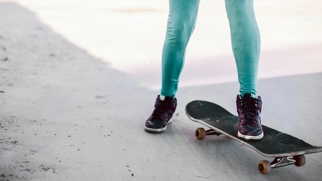 Ragazza in leggings turchese in piedi sullo skateboard