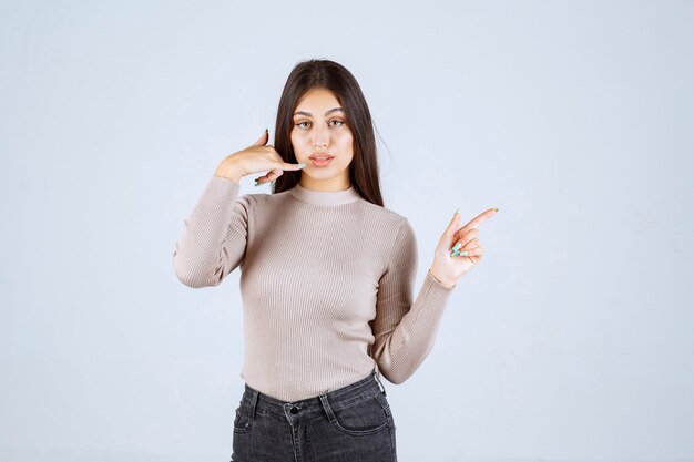 Ragazza in maglione grigio che chiede di chiamare.