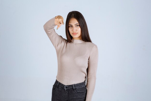 Ragazza in maglione grigio che dà pose cattive e seducenti.