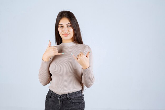 Ragazza in maglione grigio che fa pollice sul segno.