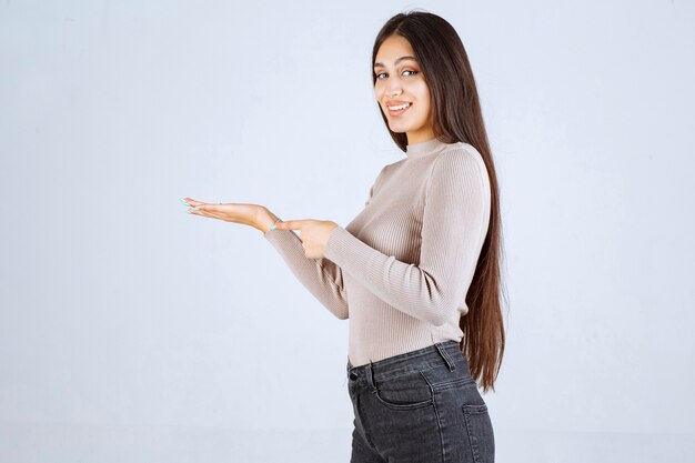 Ragazza in maglione grigio che guarda a qualcosa alla sua mano.