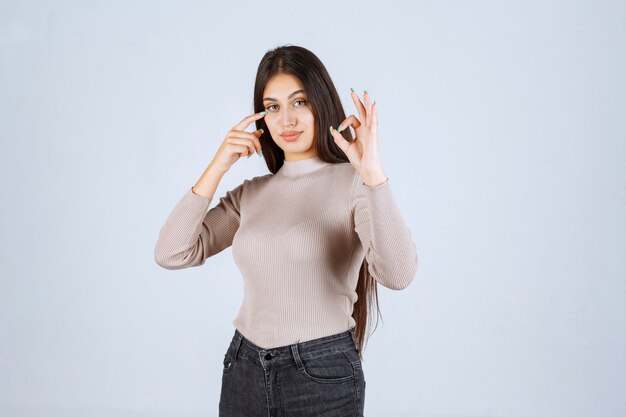 Ragazza in maglione grigio che mostra il segno giusto del cerchio.