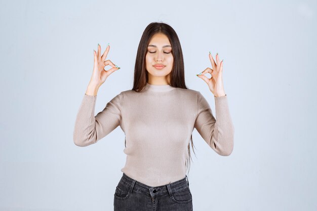 Ragazza in maglione grigio che mostra il segno giusto del cerchio.