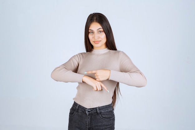 Ragazza in maglione grigio che mostra il suo tempo.