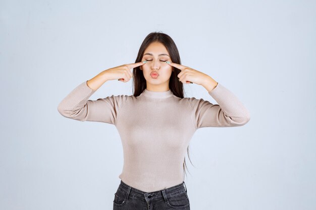 Ragazza in maglione grigio che punta la testa.