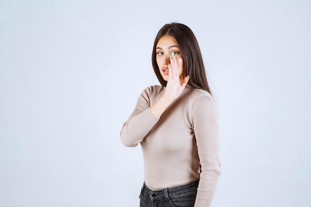 Ragazza in maglione grigio spettegolare cose segrete.