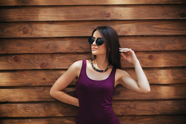 Ragazza in occhiali da sole e camicia viola in posa