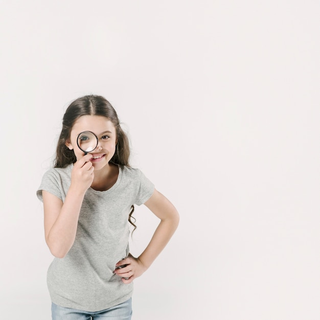 Ragazza in piedi in studio con lente di ingrandimento