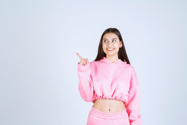 Ragazza in pigiama rosa che punta a sinistra