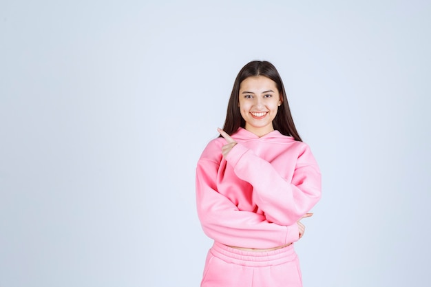 Ragazza in pigiama rosa che punta a sinistra