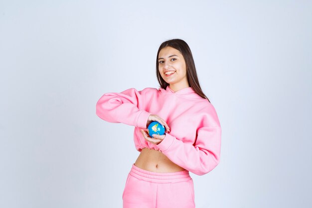 Ragazza in pigiama rosa che tiene un mini globo tra le mani.