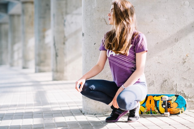 Ragazza in posa con uno skateboard