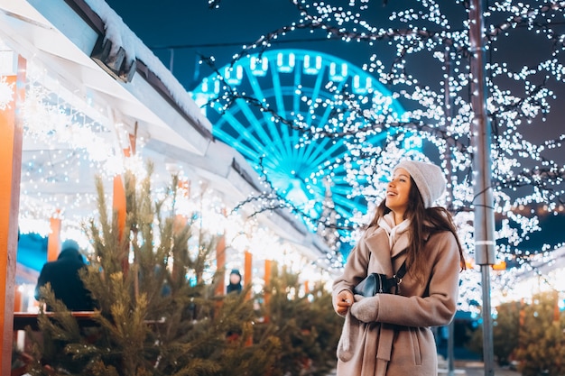 Ragazza in posa sullo sfondo di alberi decorati