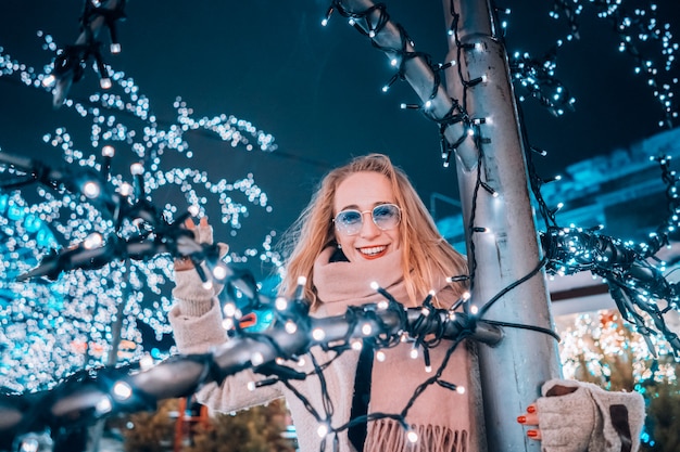 Ragazza in posa sullo sfondo di alberi decorati