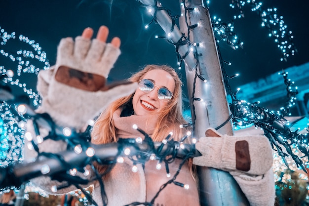 Ragazza in posa sullo sfondo di alberi decorati