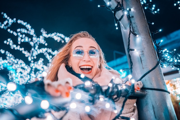 Ragazza in posa sullo sfondo di alberi decorati