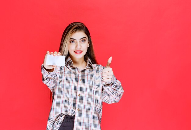 Ragazza in possesso di un biglietto da visita e che mostra segno di soddisfazione