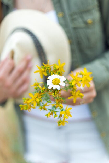 Ragazza in possesso di un mazzo di fiori gialli nel parco.