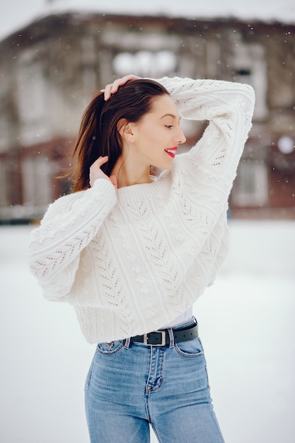 Ragazza in un maglione bianco che sta in un parco di inverno