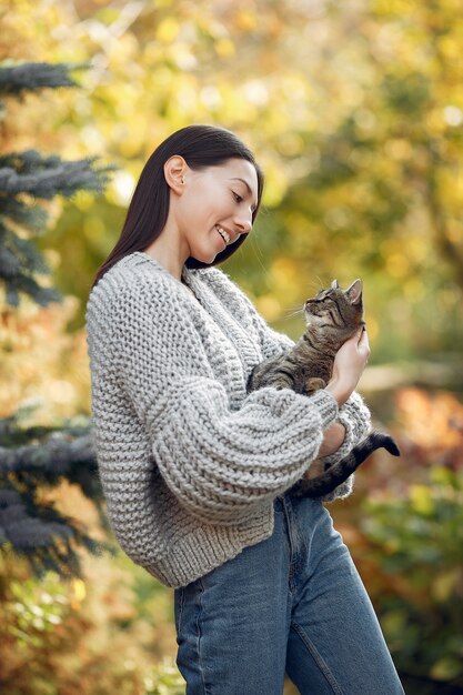 Ragazza in un maglione grigio che posa all'aperto con un gatto