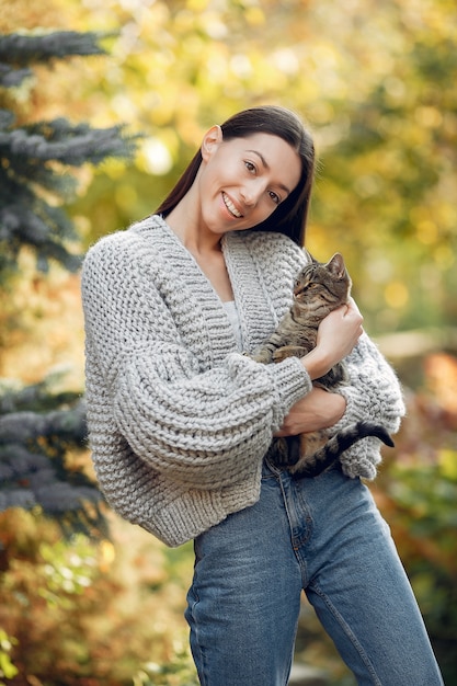 Ragazza in un maglione grigio che posa all'aperto con un gatto