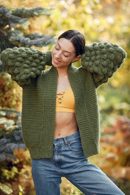 Ragazza in un maglione verde che posa all'aperto