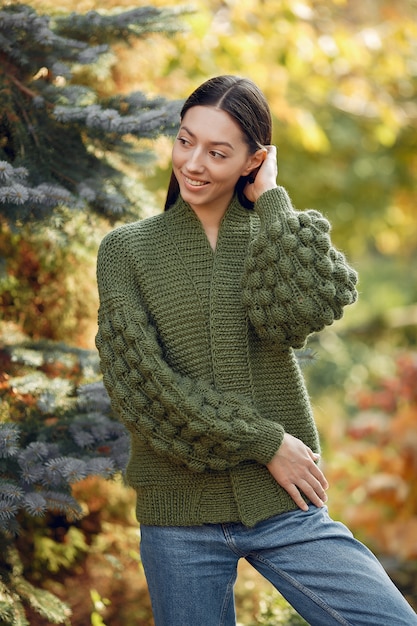 Ragazza in un maglione verde che posa all'aperto