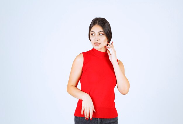 Ragazza in una camicia rossa che dà pose positive e seducenti.