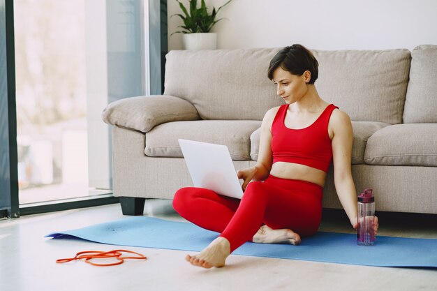 Ragazza in uniforme sportiva rossa praticando yoga a casa