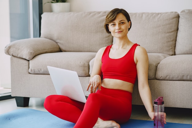 Ragazza in uniforme sportiva rossa praticando yoga a casa