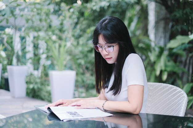 ragazza indossare occhiali leggere un libro in giardino