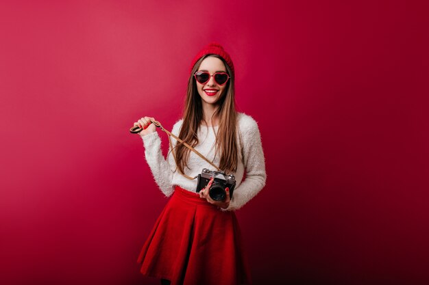 Ragazza interessata con capelli castani dritti lucidi che sorride sullo spazio bordeaux