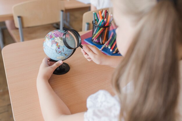 Ragazza irriconoscibile esaminando il globo