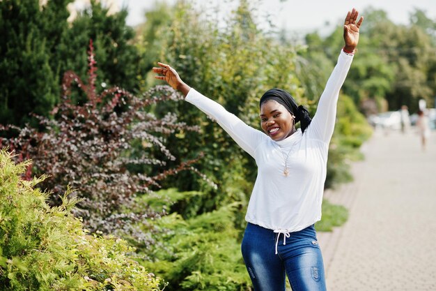 Ragazza musulmana africana in felpa bianca hijab nera e jeans posati all'aperto