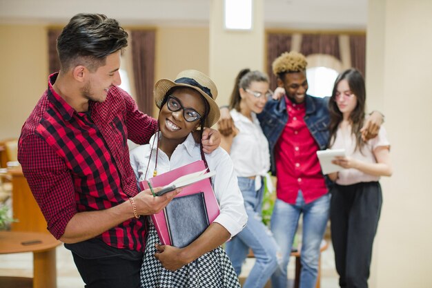 Ragazza nera affascinante abbracciata con lo studente