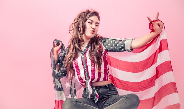 Ragazza patriottica con la bandiera dell'America su una parete colorata