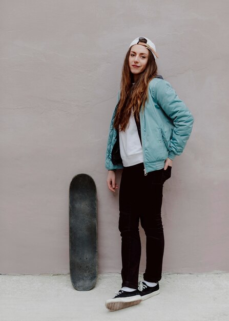 Ragazza pattinatrice all'aperto e il suo skateboard