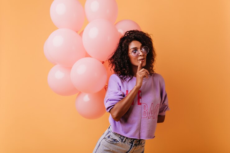 Foto gratuito ragazza pensierosa con un mazzo di palloncini di partito in posa sull'arancio. signora affascinante che celebra il compleanno.